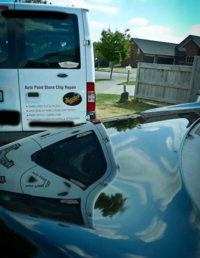 Close up of bonnet with van reflecting on surface